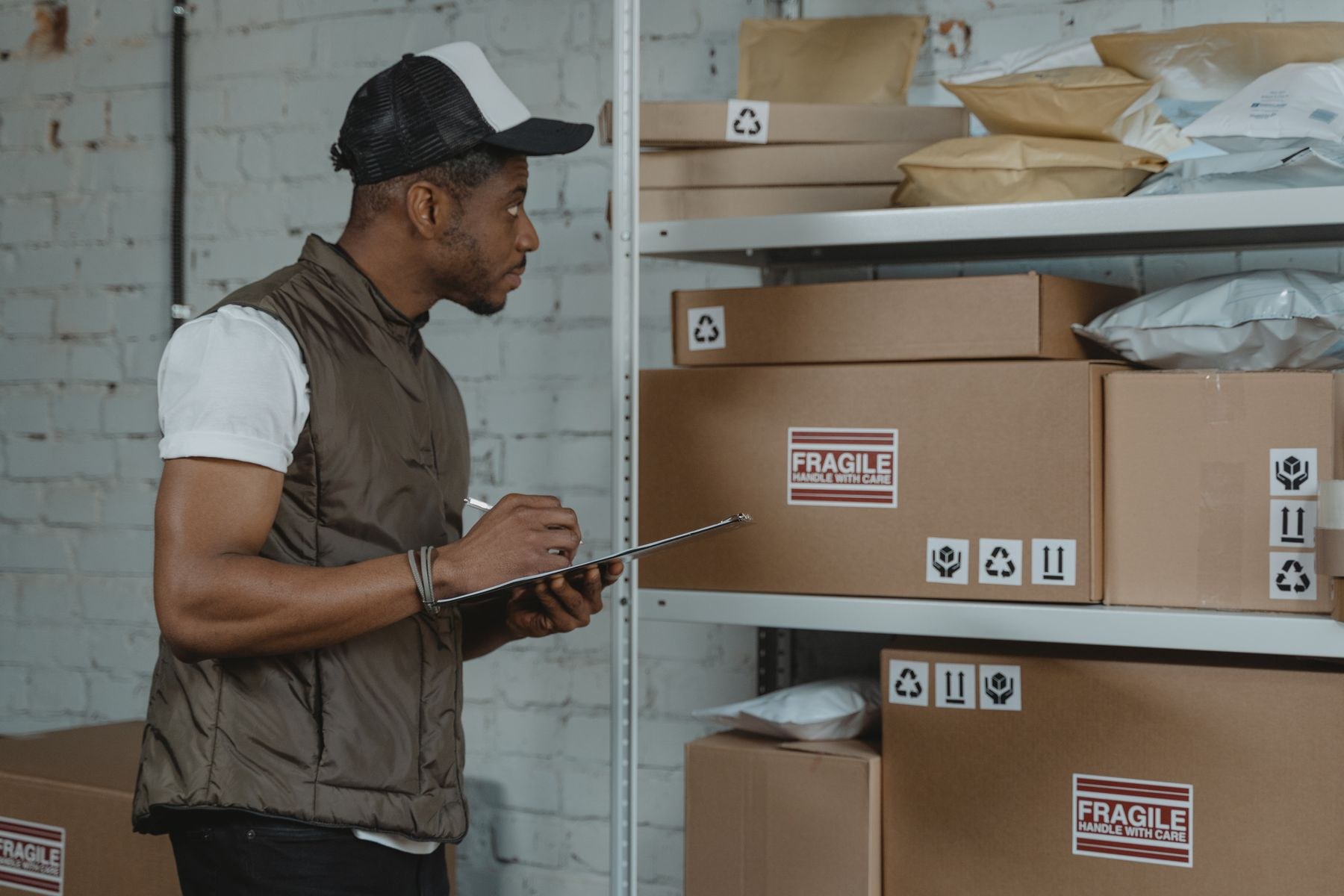Warehouse worker checking boxes on shelves and taking notes on a clipboard